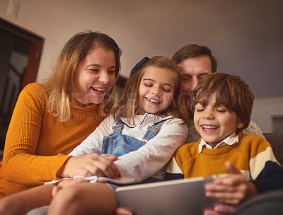 Buy stock photo Cropped shot of an affectionate young family of four using a digital tablet while sitting on the sofa at home