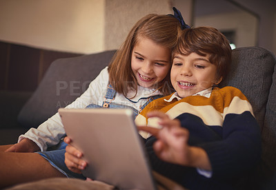 Buy stock photo Cropped shot of an adorable little boy and his older sister using a digital tablet while sitting on the sofa at home