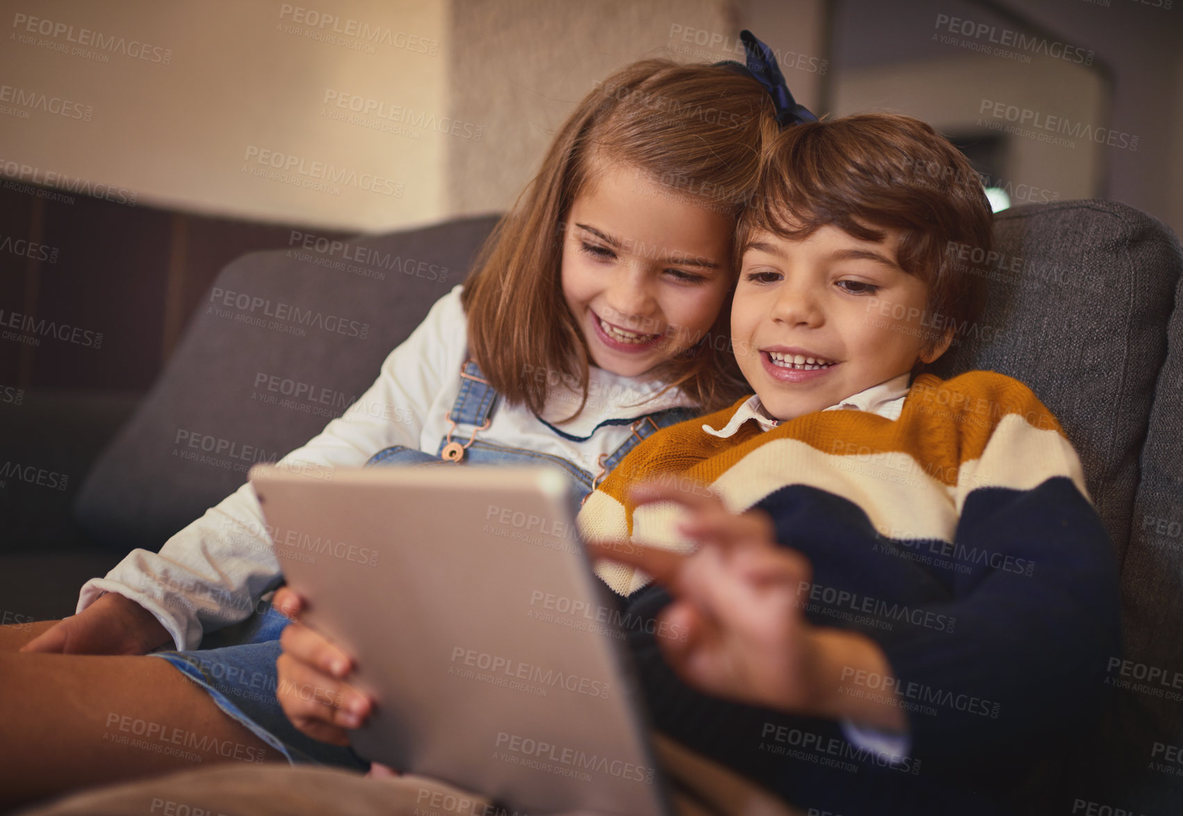 Buy stock photo Cropped shot of an adorable little boy and his older sister using a digital tablet while sitting on the sofa at home