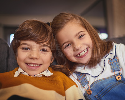 Buy stock photo Cropped portrait of an adorable little boy and his older sister sitting on the sofa at home