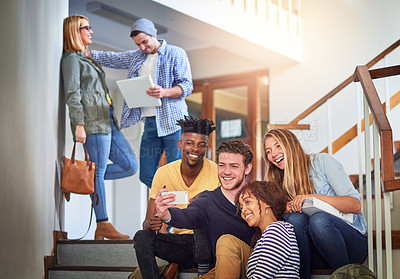 Buy stock photo Shot of a group of university students taking a selfie on the staircase at campus
