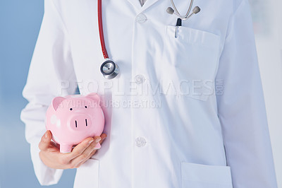 Buy stock photo Cropped shot of an unrecognizable female doctor holding a piggybank while standing in the hospital