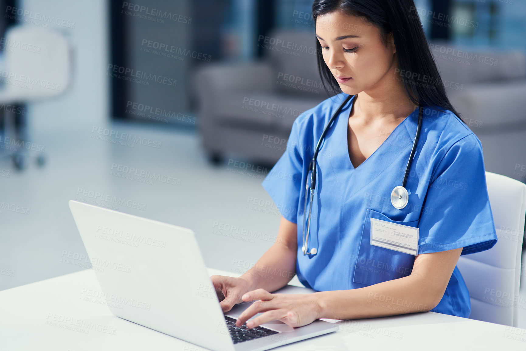 Buy stock photo Cropped shot of an attractive young female nurse using a tablet while sitting at her desk in the hospital