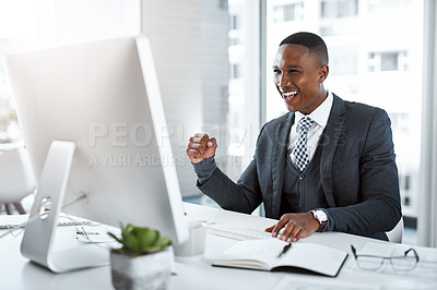 Buy stock photo Shot of a young businessman using a computer and cheering at his desk in a modern office