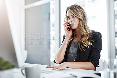 Buy stock photo Shot of a young businesswoman using a mobile phone and computer at her desk in a modern office