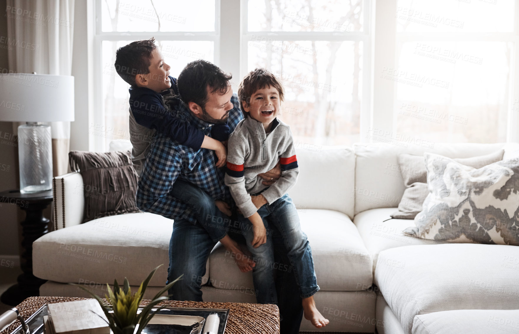 Buy stock photo Happiness, playful and father with children on the sofa for playing, quality time and crazy fun. Love, happy and boy kids piling onto their dad with energy on the couch of their family home together