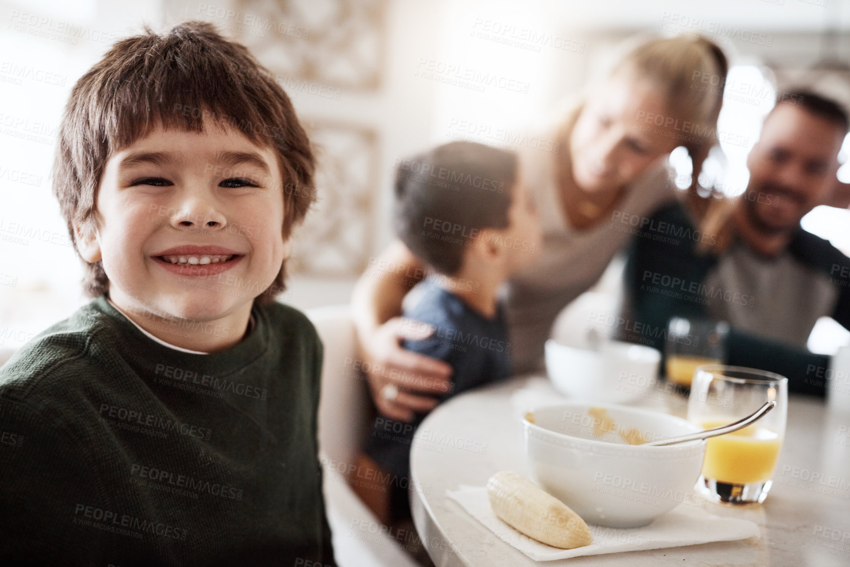 Buy stock photo Portrait of a happy little boy enjoying breakfast together with his family at home