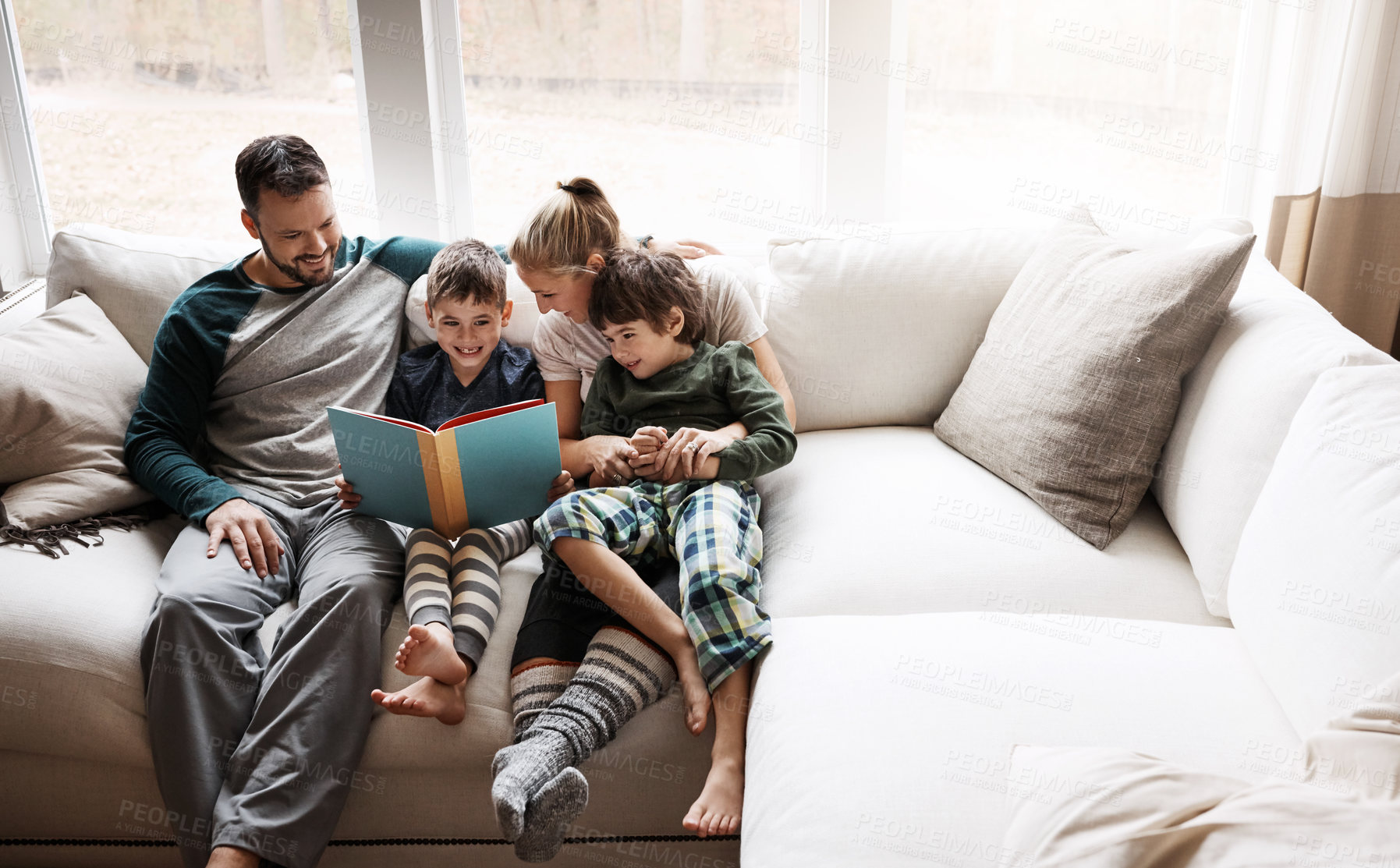 Buy stock photo Happy, learning and parents reading a book with children for bonding, fun and quality time. Knowledge, information and boys excited about a story on the lounge sofa with their mother and father