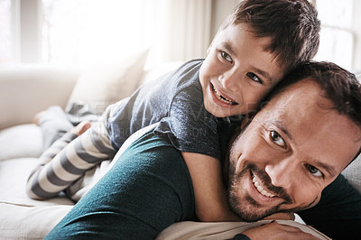 Buy stock photo Shot of an adorable little boy having fun with his father on the sofa at home