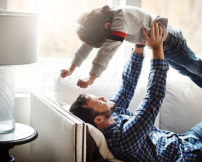 Buy stock photo Happy, father and lifting kid on home sofa for bonding, wellness and play together with smile. Dad playing flying in air game with son on living room couch for care, love and bond in family home