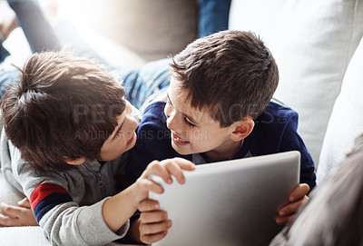 Buy stock photo Shot of two adorable brothers using a digital tablet together while relaxing on the sofa at home