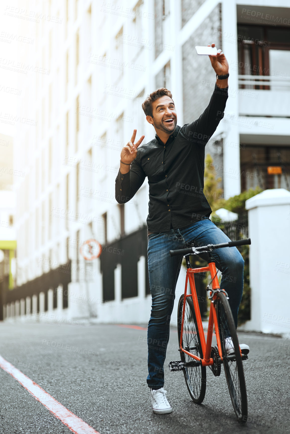Buy stock photo Full length shot of a handsome young man taking selfies while traveling through the city by bike