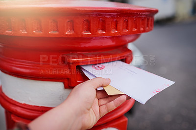 Buy stock photo Closeup of an unrecognizable person's hand sliding in letters into a red mailbox outside during the day