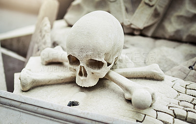 Buy stock photo Closeup of a skull statue on a grave at a graveyard outside during the day