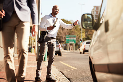 Buy stock photo Cropped shot of a handsome young businessman hailing a ride in the city