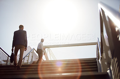 Buy stock photo Low angle shot of unrecognizable businessmen walking up stairs outside