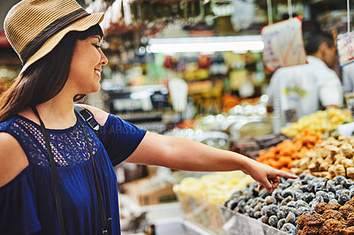 Buy stock photo Shot of a cheerful young woman browsing through a market deciding what to buy outside during the day