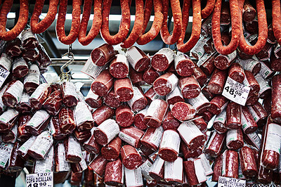Buy stock photo Shot of different types of cured meats stacked on top of each other at a stall to be sold at a market during the day