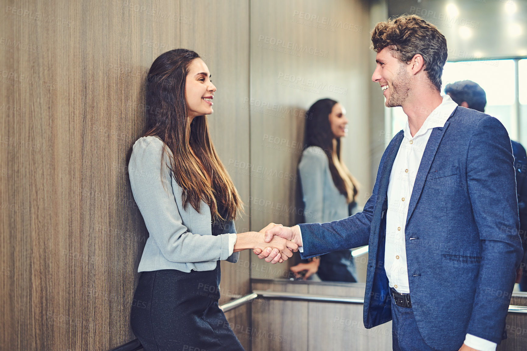 Buy stock photo Cropped shot of a businessman and businesswoman greeting by handshake in an elevator