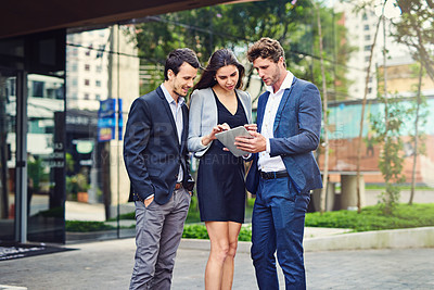 Buy stock photo Shot of businesspeople using a tablet outside
