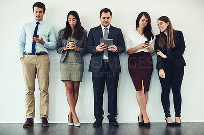 Buy stock photo Studio shot of a group of businesspeople using wireless technology while standing in line