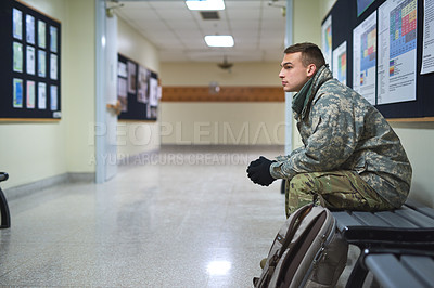 Buy stock photo Shot of a young soldier sitting on a bench in the hall of a military academy