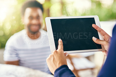 Buy stock photo Shot of an unrecognizable woman browsing on a digital tablet while being seated at a cafe during the day