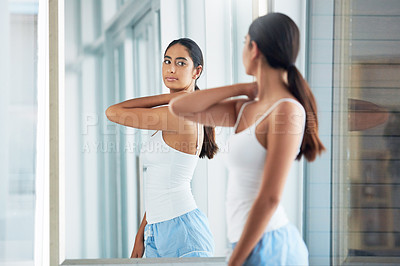 Buy stock photo Cropped shot of an attractive young woman inspecting her back in front of the bathroom mirror