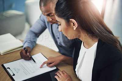 Buy stock photo Shot of two businesspeople going through some paperwork in an office