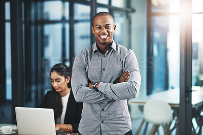 Buy stock photo Portrait of a young businessman standing in an office with his colleague in the background