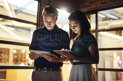 Buy stock photo Cropped shot of two young designer using their digital tablets while working late in the office