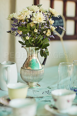 Buy stock photo Shot of a metal vase filled with flowers on a table at a tea party inside