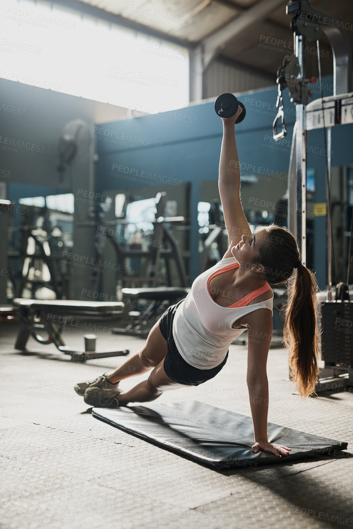 Buy stock photo Shot of a young woman working out with weights at the gym