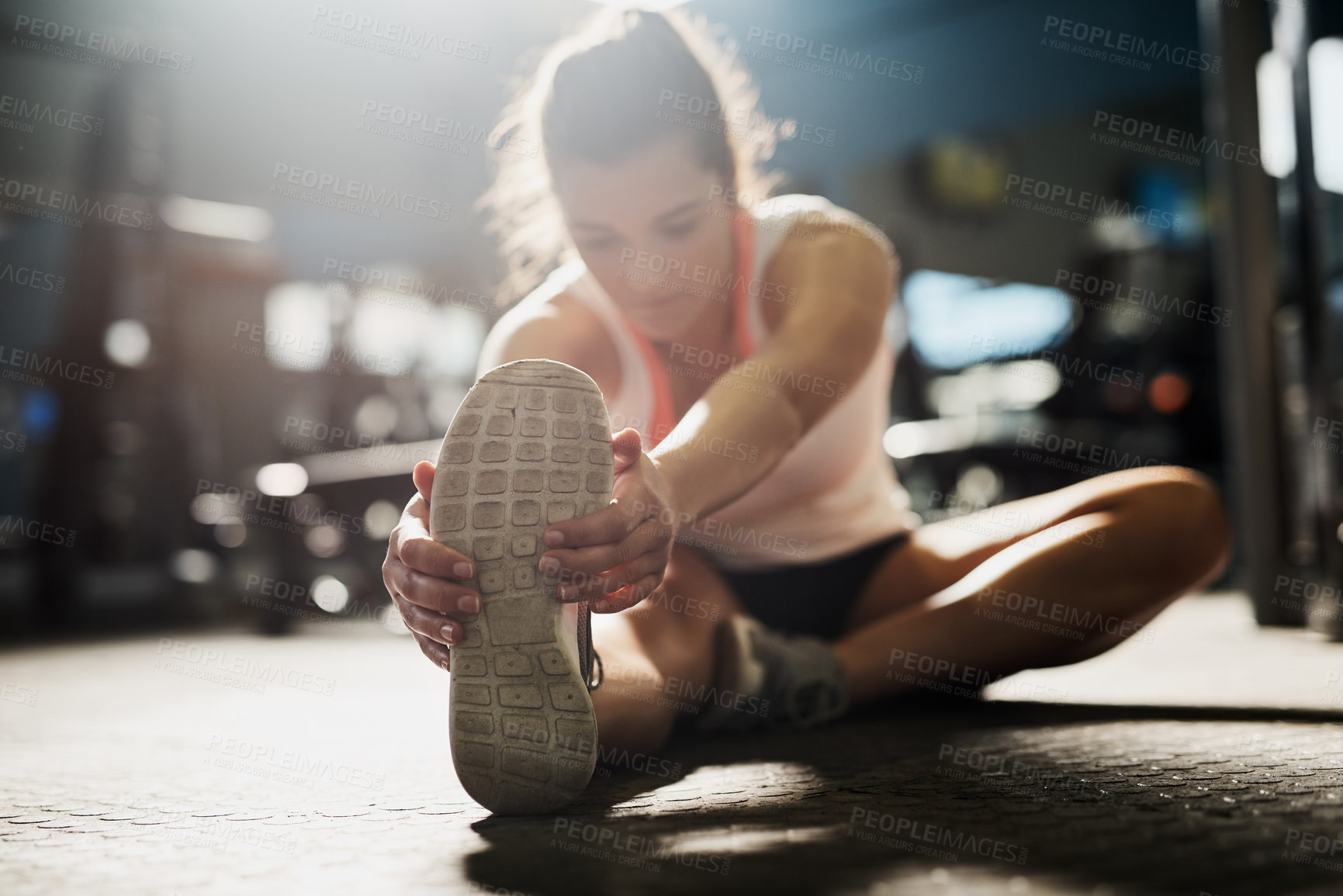 Buy stock photo Shot of a young woman doing stretch exercises at the gym