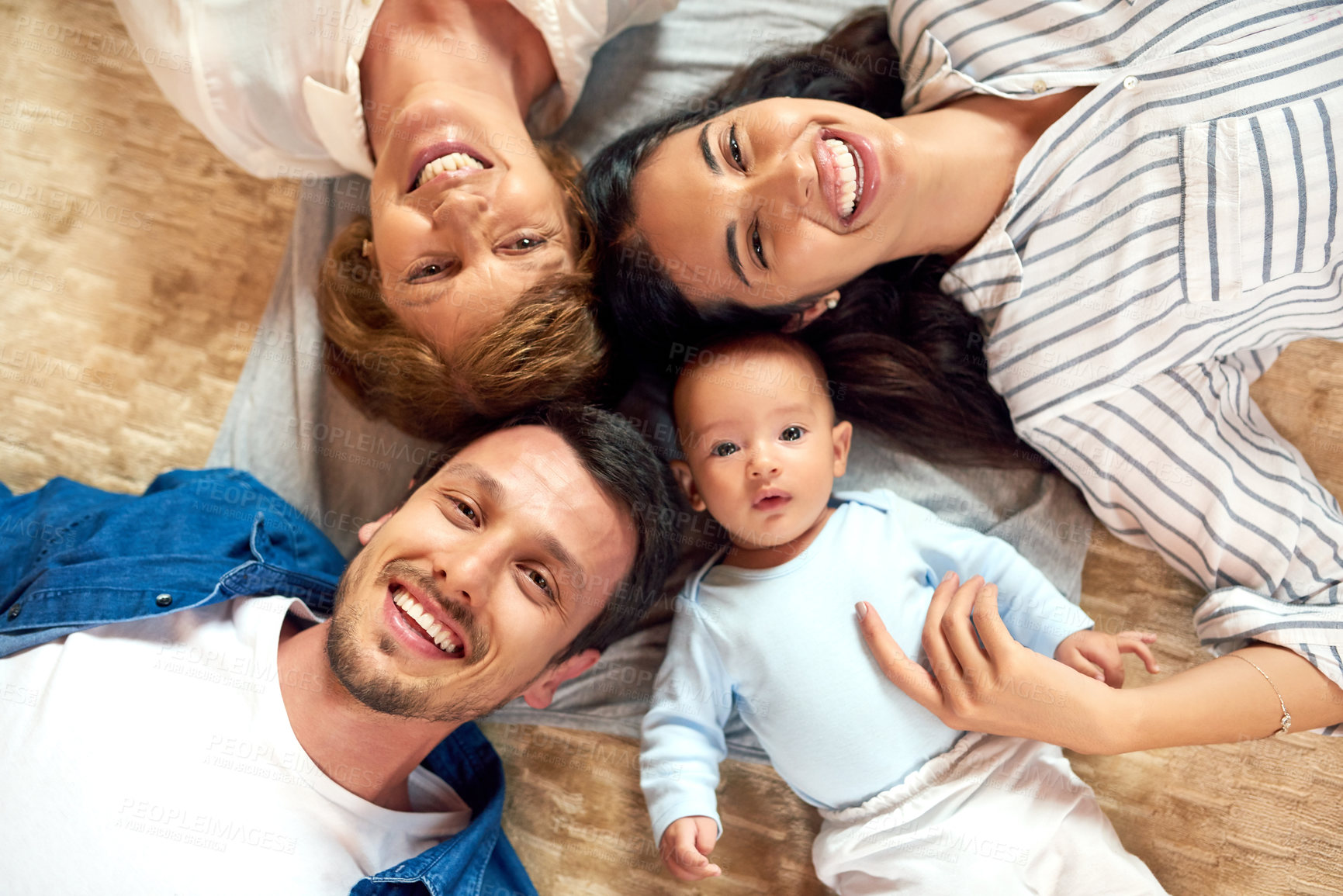 Buy stock photo High angle portrait of an affectionate family of five lying down on the living room floor