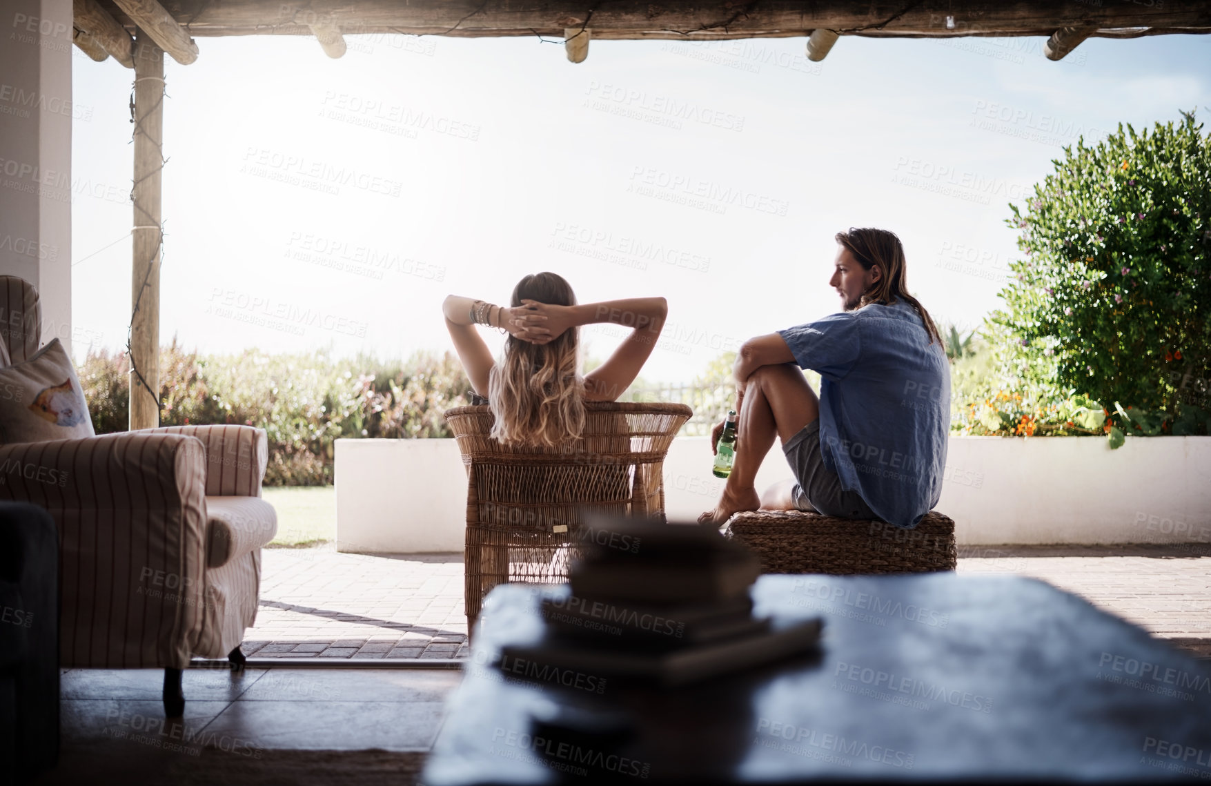 Buy stock photo Rearview shot of a young couple chilling outside on the veranda at home
