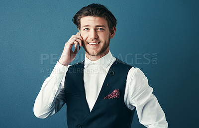 Buy stock photo Studio shot of a handsome young businessman making a phonecall against a blue background