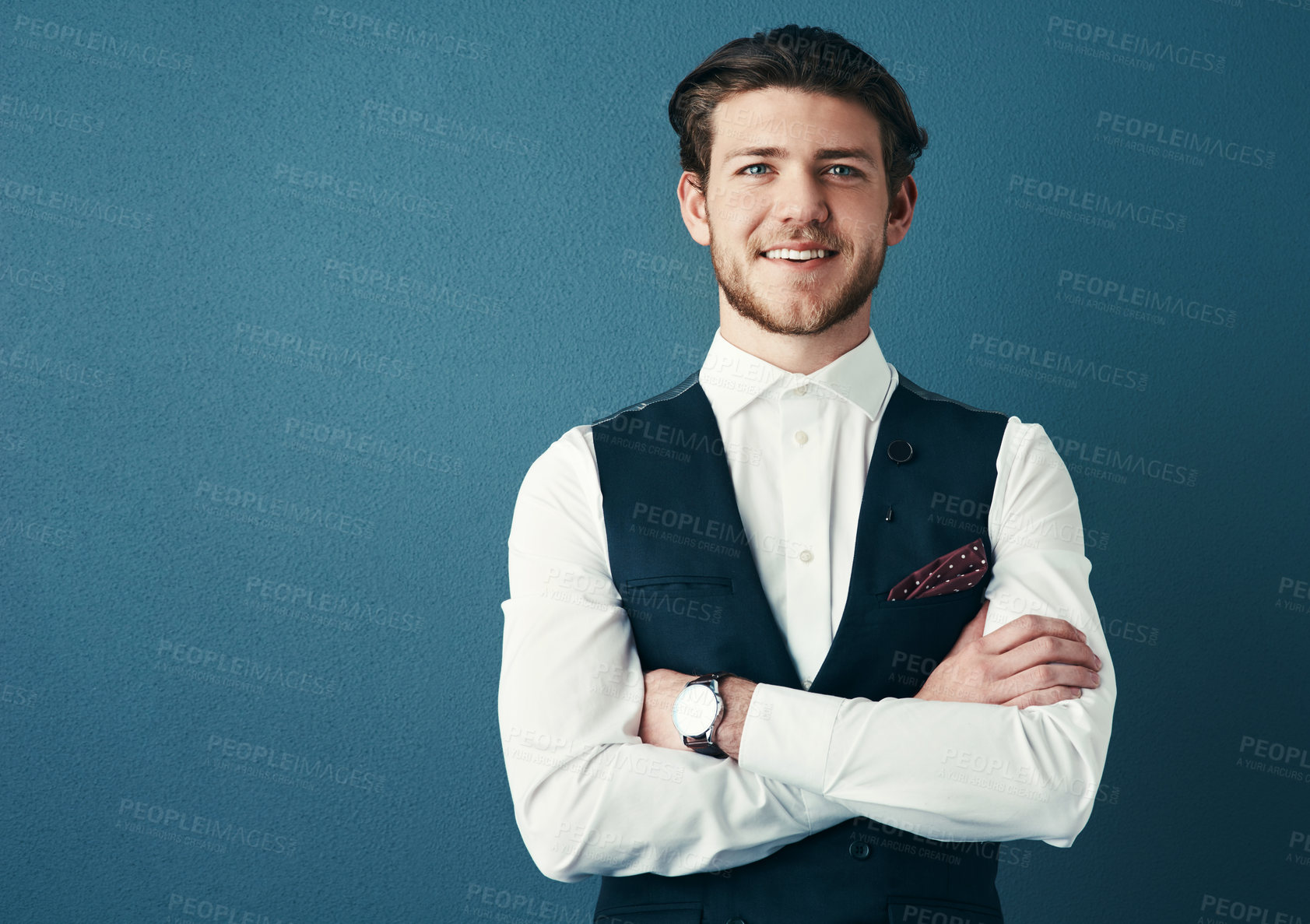 Buy stock photo Studio shot of a handsome young businessman standing with his arms crossed against a blue background