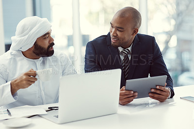 Buy stock photo Shot of two businessmen using a digital tablet and laptop while having a discussion in a modern office