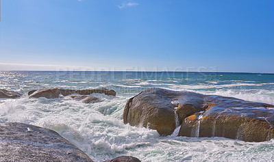 Buy stock photo Scenic view of ocean waves and water washing over boulders and rocks in Camps Bay, Cape Town, South Africa. Empty tropical seascape with blue sky and copy space. Travel, tourism abroad and overseas