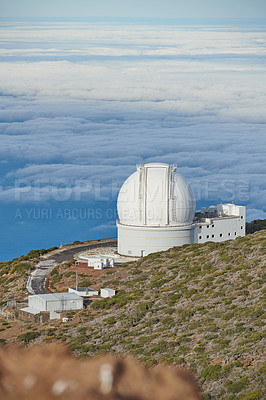 Buy stock photo An astronomical observatory on a mountain top with blue sky copy space. Telescope surrounded by greenery and located on an island at the edge of cliff. Roque de los Muchachos Observatory in La Palma