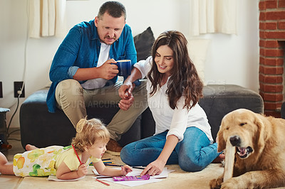 Buy stock photo Cropped shot of a young mother and father helping their adorable little daughter colour in and draw in the living room at home