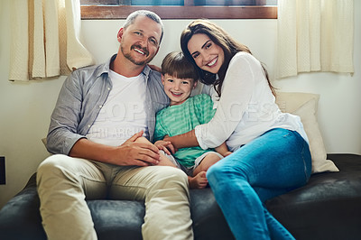Buy stock photo Portrait of a young mother and father spending time with their adorable little son on the sofa in the living room at home