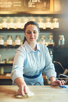 Buy stock photo Shot of a young woman cleaning a countertop in her cafe