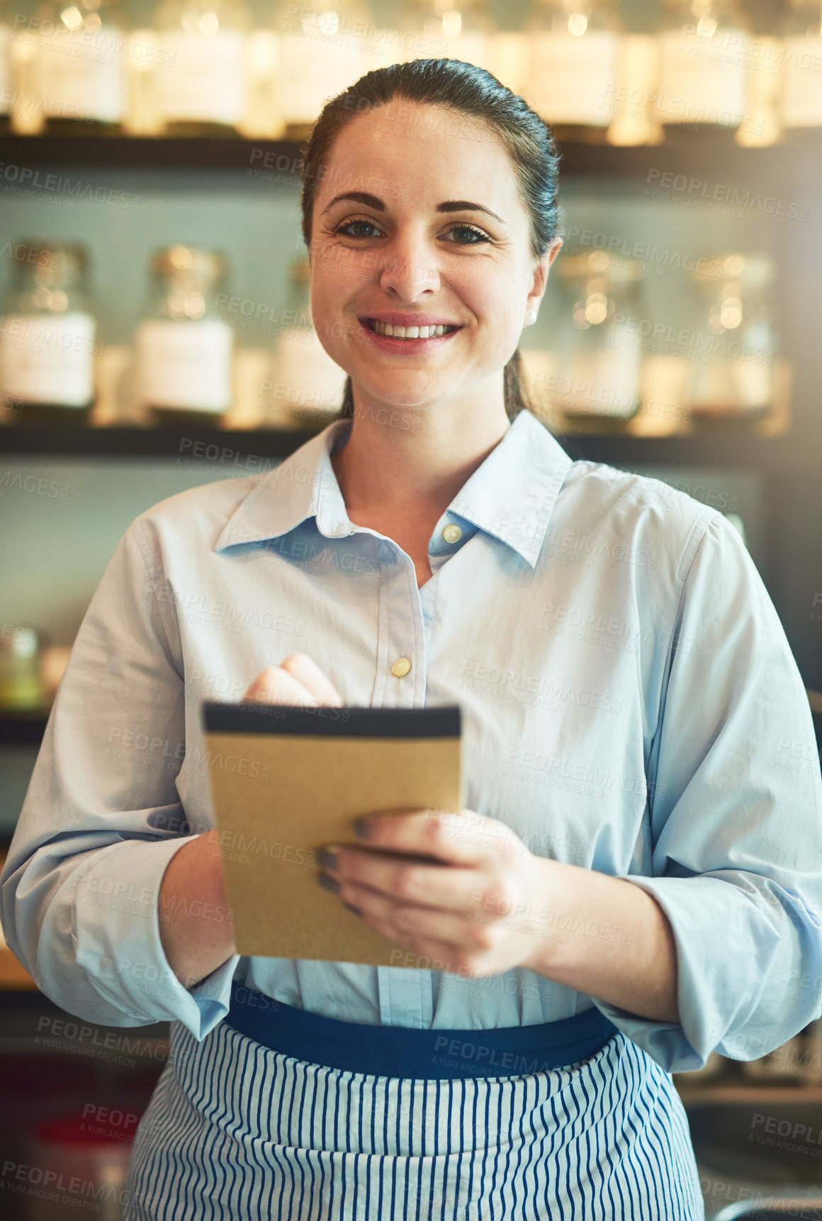 Buy stock photo Portrait of a young waitress holding a notebook in a cafe