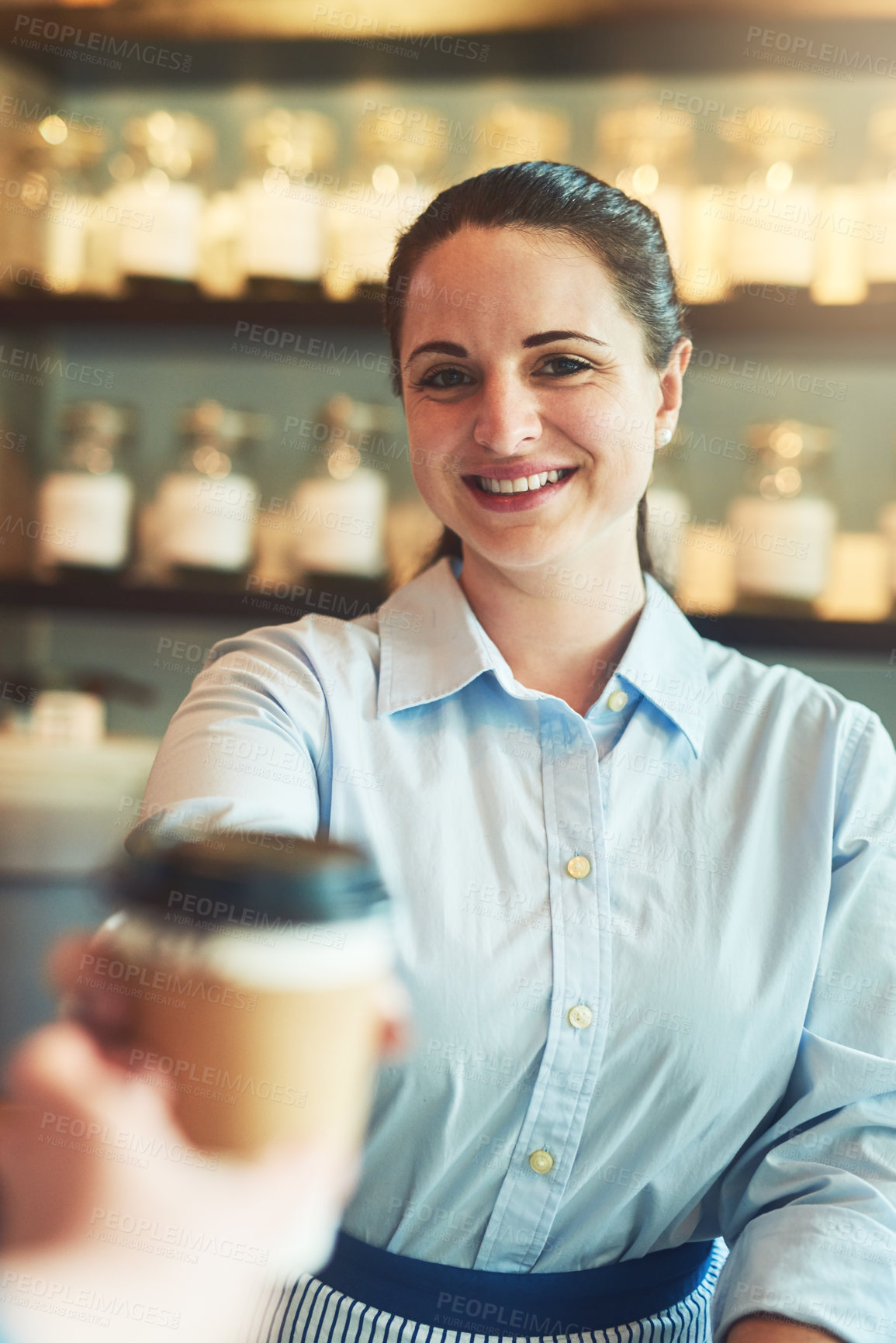 Buy stock photo Portrait of a young barista giving a cup of coffee to a customer in a cafe