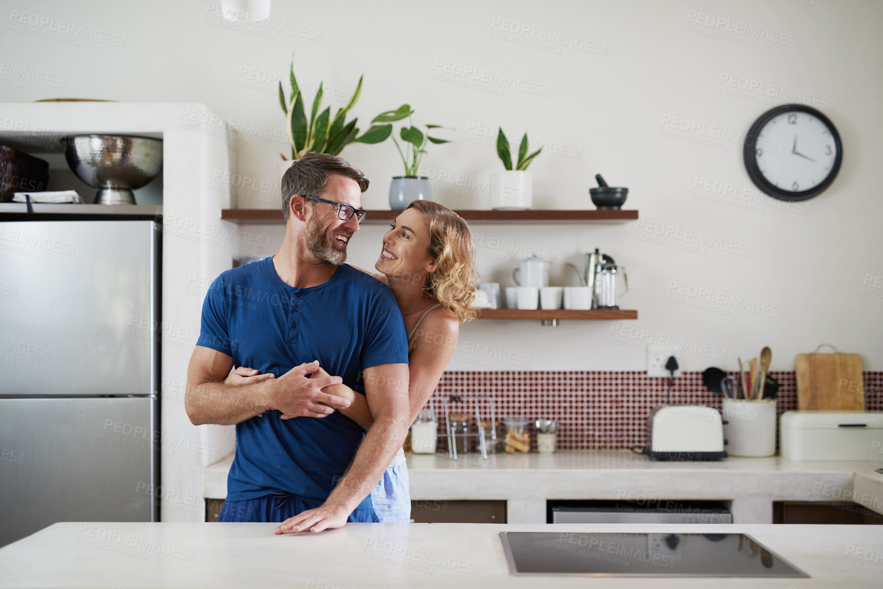 Buy stock photo Shot of a happy middle aged couple embracing in the kitchen at home