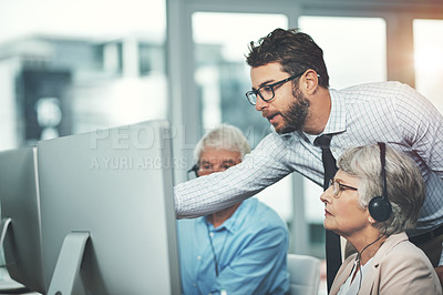 Buy stock photo Shot of a young man helping his senior colleagues in a call center