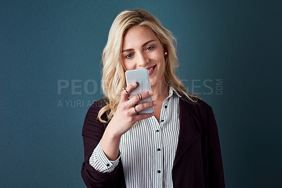 Buy stock photo Studio shot of a beautiful young businesswoman using a cellphone against a blue background