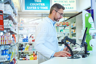 Buy stock photo Cropped shot of a handsome mature male pharmacist working in a pharmacy